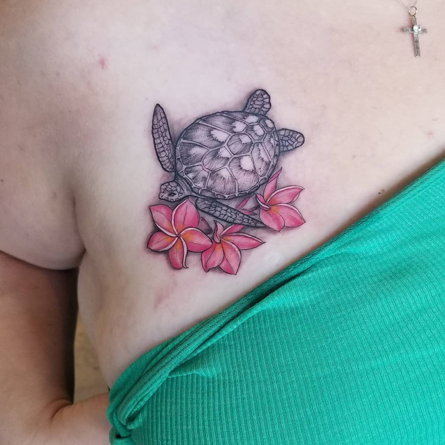 Tattoo of a sea turtle and flowers on a chest